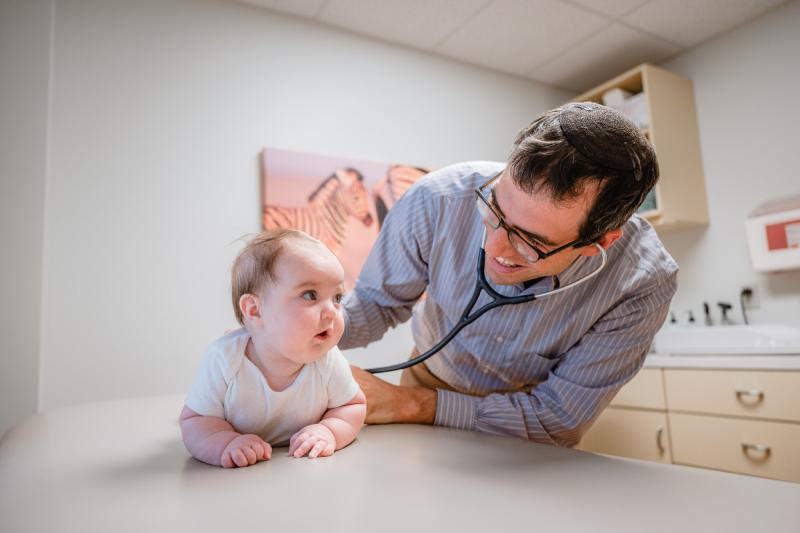 a pediatrician using a stethoscope on a baby crawling